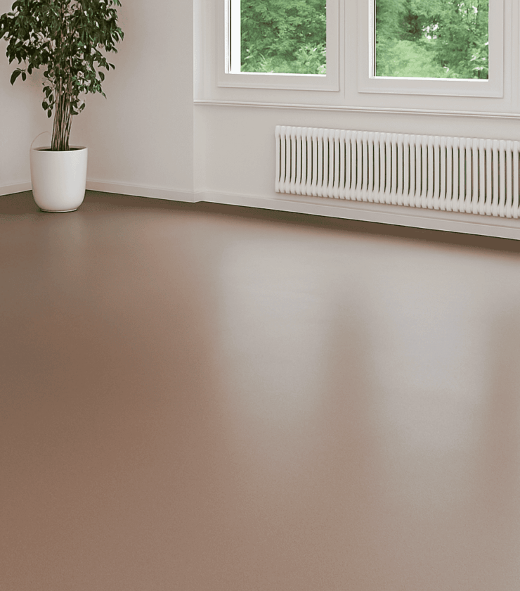 Emissionsarmer Epoxidharzboden in einem hellen Wohnraum mit großen Fenstern und Zimmerpflanze